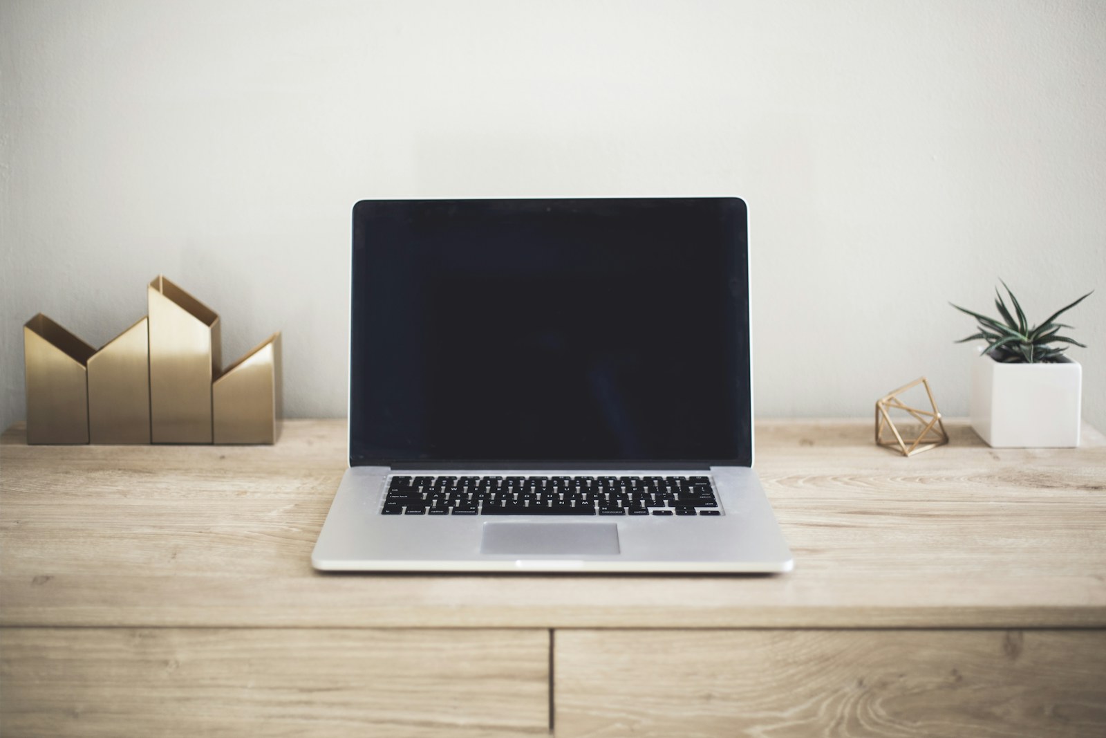 A laptop on a desk beside a notebook